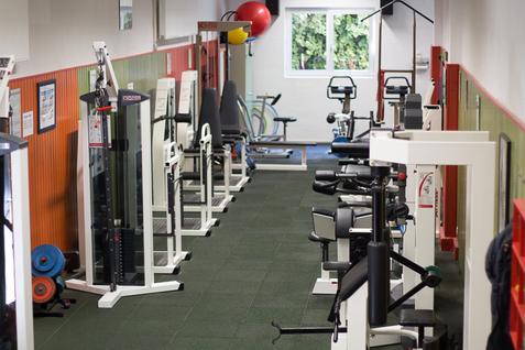 Übersicht der Ausstattung im Kraftraum der Jahnhalle Blick auf die gesamte Ausstattung des Kraftraums in der Jahnhalle, mit verschiedenen Trainingsgeräten entlang der Wände.