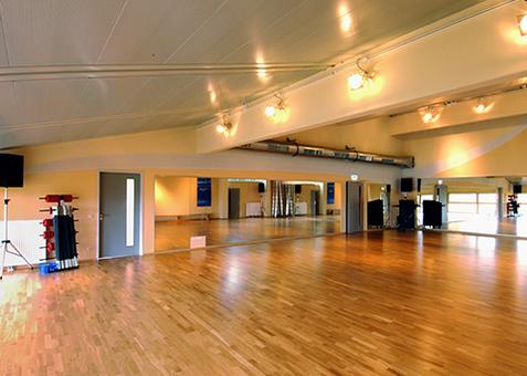 Kursraum im TV Vital Großer Kursraum im TV Vital mit Holzboden, Spiegelwand und heller Beleuchtung.