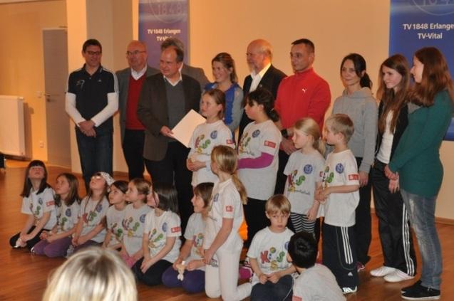 Gründung KISS Eine Gruppe von Erwachsenen und Kindern posiert gemeinsam für ein Foto in einem Raum für die Gründung von KISS.