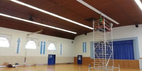 Beleuchtungs Montage in der Haupthalle Eine Person montiert eine neue Beleuchtung in der Haupthalle der Jahnhalle auf einem Gerüst.