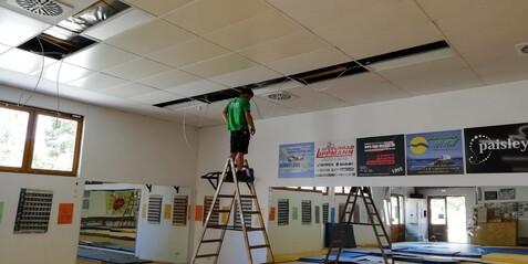 Beleuchtungs-Montage in der Judohalle Eine Person steht auf einer Leiter und montiert die Beleuchtung an der Decke der Judohalle der jahnhalle.