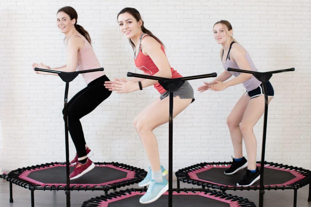 Trampolin-Training in der Gruppe Drei Frauen springen auf Mini-Trampolinen während eines Fitness-Workouts.